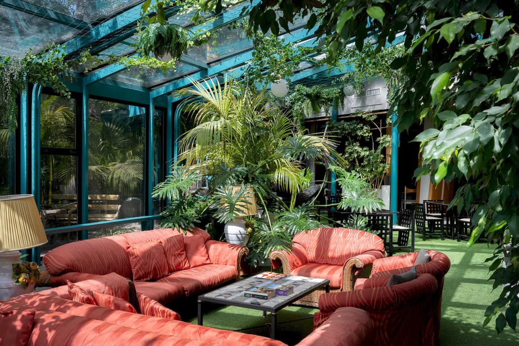 Salottino interno del Grand Hotel Panoramic con grandi vetrate e piante verdi